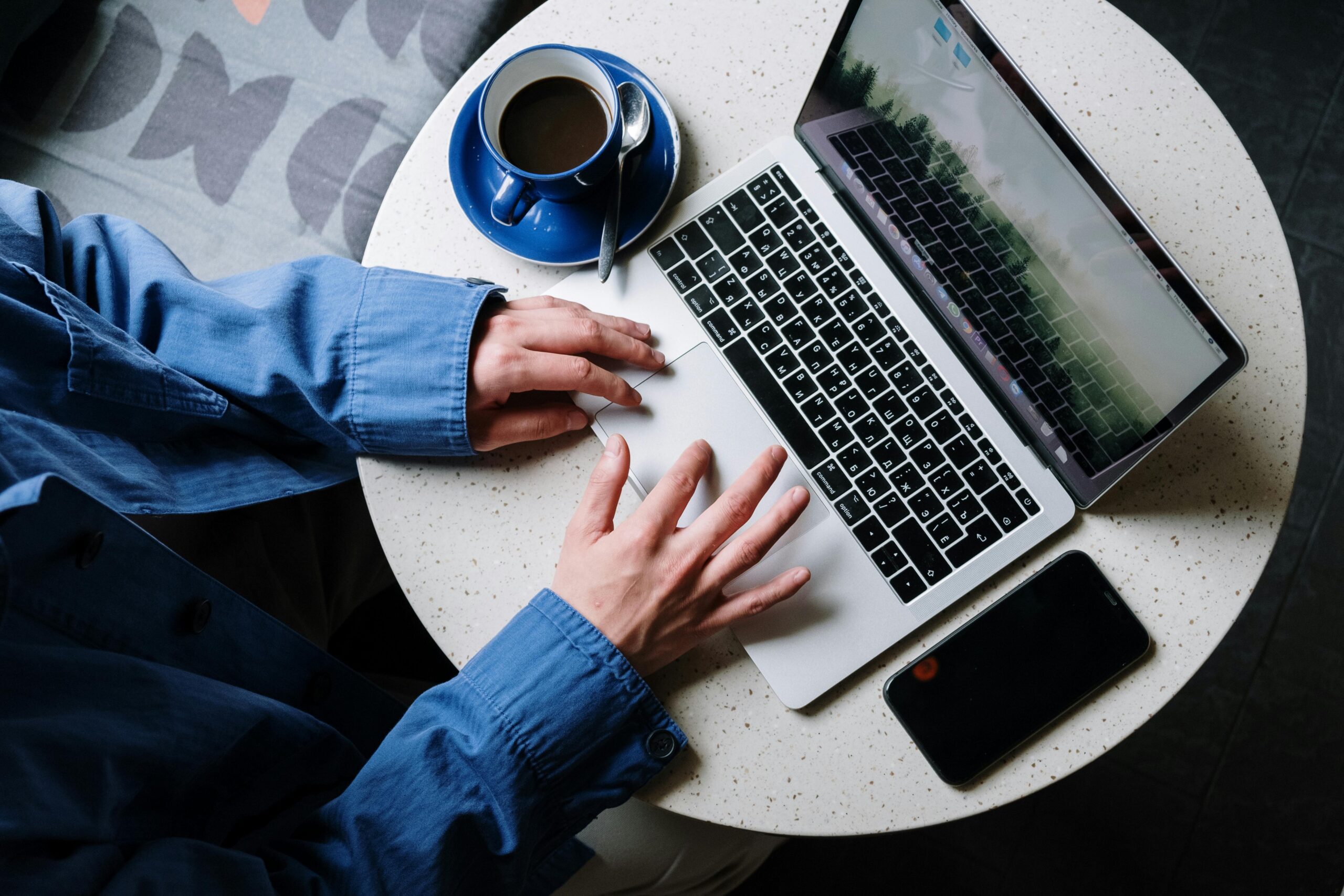A person working on a laptop beside a cup of coffee, showcasing modern digital life.